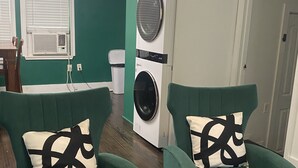 Une pièce avec deux fauteuils verts, un lave-linge et une petite table.