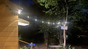 Un espace extérieur aménagé en terrasse, avec des guirlandes lumineuses, une table et des chaises.
