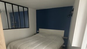 A bedroom with a bed, a nightstand, a mirror, and a radiator.