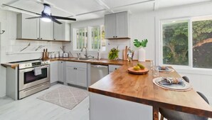 A modern kitchen with white cabinetry, a wooden countertop, and a built-in oven. - Mountain Oasis: Modern Plantation Home (Kealakekua)
