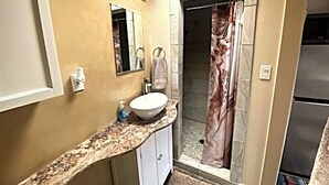 Ein Badezimmer mit Marmorplatte, Waschbecken, Spiegel, Duschvorhang und Handtuchhalter.