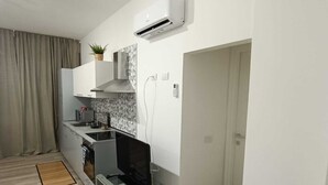 A modern kitchen with a built-in stove, a microwave, and a small dining area. - Appartamento Daisy - Parma (Parma)