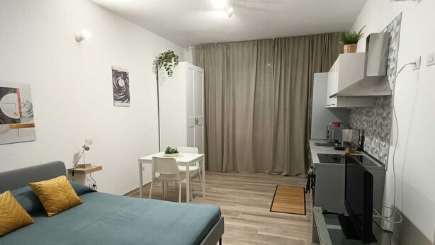 A modern bedroom with a bed, a desk, and a kitchenette. - Appartamento Daisy - Parma (Parma)