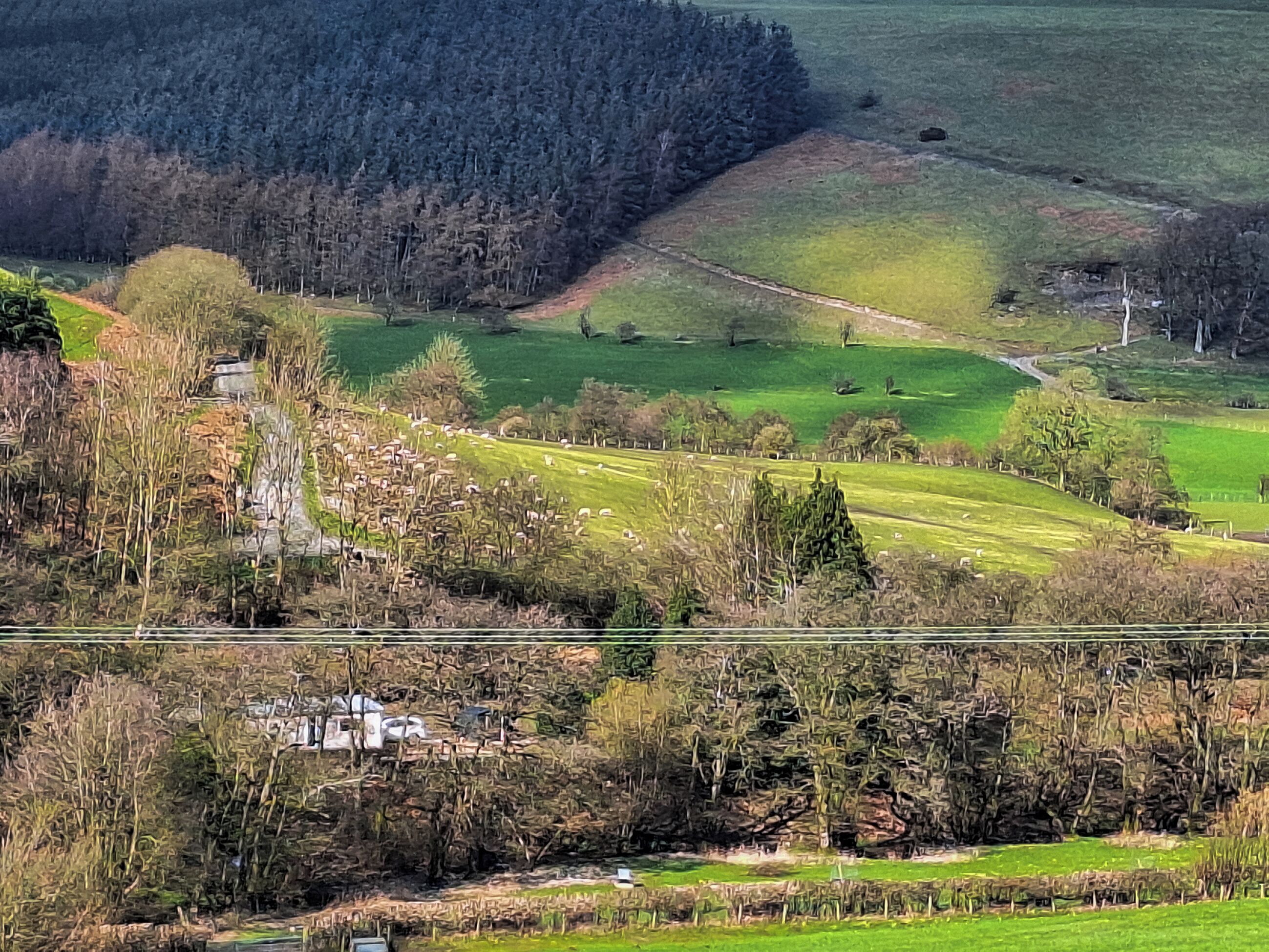 A rural landscape with fields, trees, and a small building.