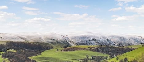 Paisaje rural con colinas ondulantes, cielo despejado y un pueblo lejano.