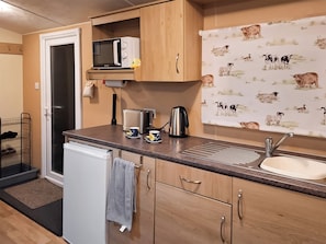 A compact kitchen with a microwave, toaster, kettle, and sink.