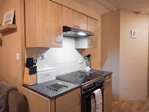 A compact kitchen with wooden cabinets, a built-in oven, and a countertop with utensils. - 2 bedroom accommodation in New Radnor, near Presteigne (New Radnor, near Presteigne)