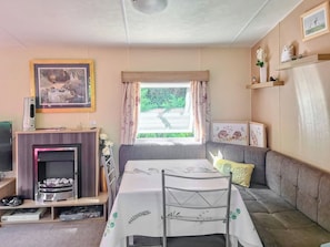 A cozy room with a sofa, a dining table, a fireplace, and a window with curtains. - 2 bedroom accommodation in New Radnor, near Presteigne (New Radnor, near Presteigne)