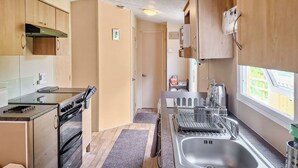 A compact kitchen with a stove, oven, sink, and window. - 2 bedroom accommodation in New Radnor, near Presteigne (New Radnor, near Presteigne)