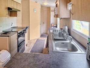 A compact kitchen with a stove, oven, sink, and window. - 2 bedroom accommodation in New Radnor, near Presteigne (New Radnor, near Presteigne)