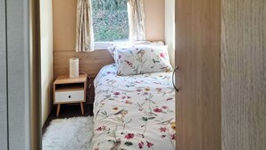 A bedroom with a bed, a nightstand, a lamp, and a window with curtains. - 2 bedroom accommodation in New Radnor, near Presteigne (New Radnor, near Presteigne)