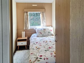 A bedroom with a bed, a nightstand, a lamp, and a window with curtains. - 2 bedroom accommodation in New Radnor, near Presteigne (New Radnor, near Presteigne)