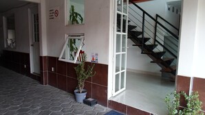 A hotel lobby with a tiled floor, a staircase, and potted plants. - Hotel María Bonita (Tlaxcala)