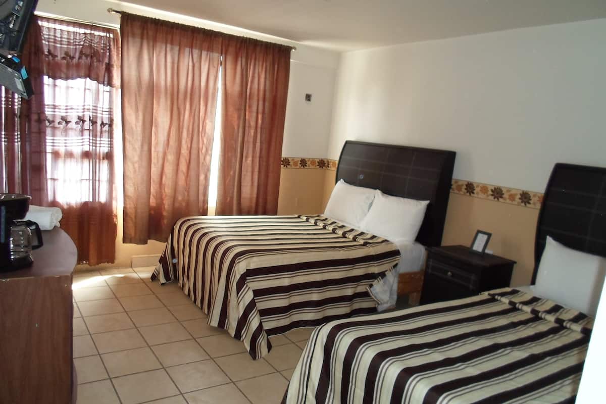 Una habitación de hotel con dos camas, cafetera y escritorio.