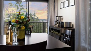 A dining table with a bottle and glasses, a vase with flowers, and a view of trees through a window. - Lakeview Golf Retreat 1BDR Condo 5057 (Williamsburg)