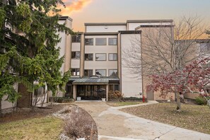 A multi-story building with a covered entrance, surrounded by trees and a grassy area. - Lakeview Golf Retreat 1BDR Condo 5057 (Williamsburg)
