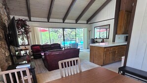 Amplia sala de estar con una mesa de comedor de madera, un sofá cómodo y una cocina con armarios de madera.