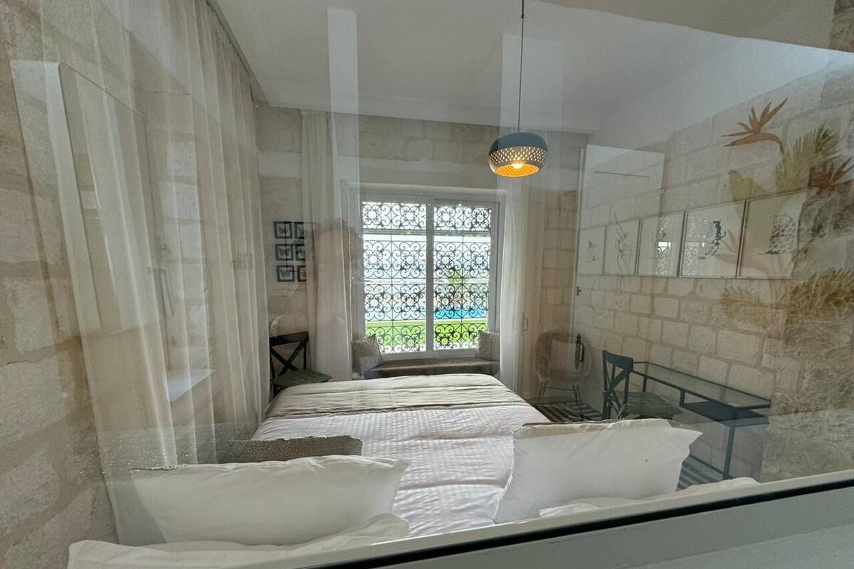 Ein Hotelzimmer mit Bett, Fenster mit Blick, einer Pendelleuchte und einem Sessel.