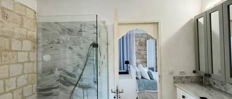A modern bathroom with a glass shower enclosure, a white vanity with a mirror, and a unique yellow pendant light.