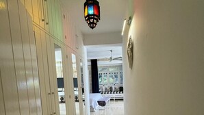 Un pasillo con ventilador de techo, una escalera y vista hacia un comedor con mesa y sillas.