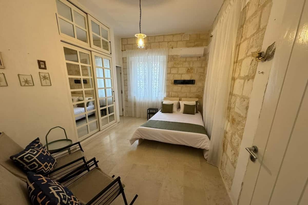 Ein Schlafzimmer mit einem Bett, einer Couch, einem Fenster mit Vorhängen und einer Steinwand.