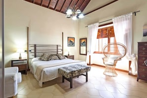 A bedroom with a bed, bedside tables, a chair, and a dresser.