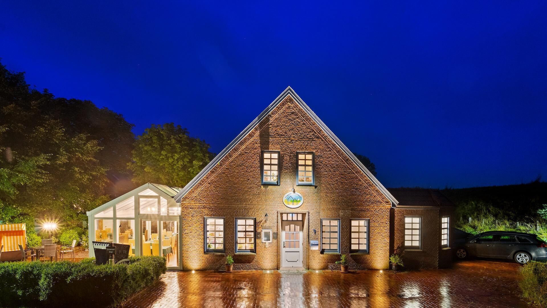 A brick building with a triangular roof, large windows, and a sign indicating it is a restaurant.