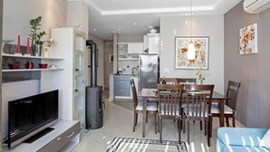 A modern living room with a flat-screen TV, dining area with wooden chairs, a glass coffee table, and a sofa. - Magical Garden with Shared Jacuzzi - Blanka A2 (Banjol)