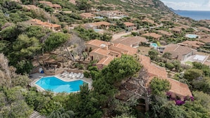 Un quartier résidentiel situé sur une colline, avec des maisons à étages, une piscine et une vue sur la mer.