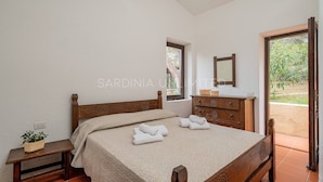 Une chambre à coucher avec un lit en bois, une table de chevet, une commode et une fenêtre.