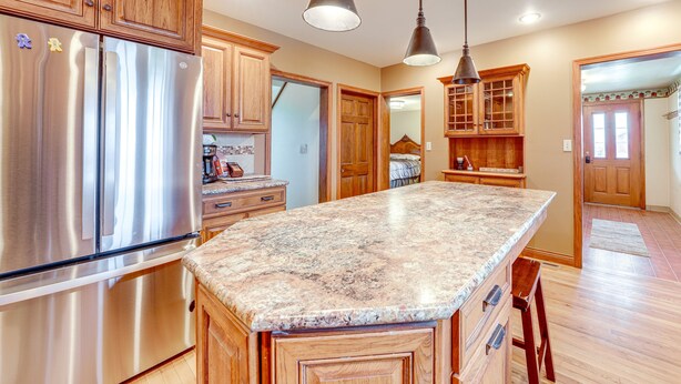 Una cocina con armarios de madera, electrodomésticos de acero inoxidable y encimeras de granito.