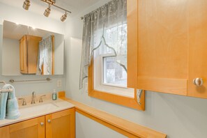 Un bagno con un mobile vanitario in legno, un lavandino, uno specchio e una finestra vista esterna.
