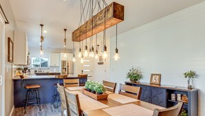 A modern kitchen with white cabinets, a wooden island, and hanging pendant lights. - 1/2 Mi to Grand Lake: Home w/ Furnished Deck! (Afton)