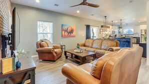 A spacious living room with leather sofas, a coffee table, and a dining area with a kitchen in the background. - 1/2 Mi to Grand Lake: Home w/ Furnished Deck! (Afton)