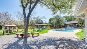 A wooden deck with picnic tables and a gazebo, a swimming pool, and a covered seating area. - Expansive Bertram Retreat w/ Pool, on 28 Acres! (Bertram)