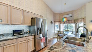 A kitchen with wooden cabinets, a stainless steel refrigerator, a built-in oven, and a granite countertop.