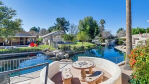 A pool area with a circular seating arrangement, a small bridge, and a view of surrounding buildings.