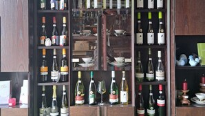 A wine cellar with multiple shelves of wine bottles, a mirror, and a rustic wooden cabinet.