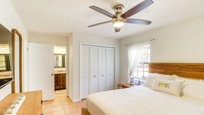 A bedroom with a bed, a ceiling fan, a wooden headboard, a nightstand, and a mirror. - Gas Grill & Fire Pit: Peaceful Dunnellon Home! (Dunnellon)