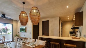 Eine moderne Küche mit einer zentralen Kochinsel, Pendelleuchten und einem Essbereich mit einem Holztisch für vier Personen.