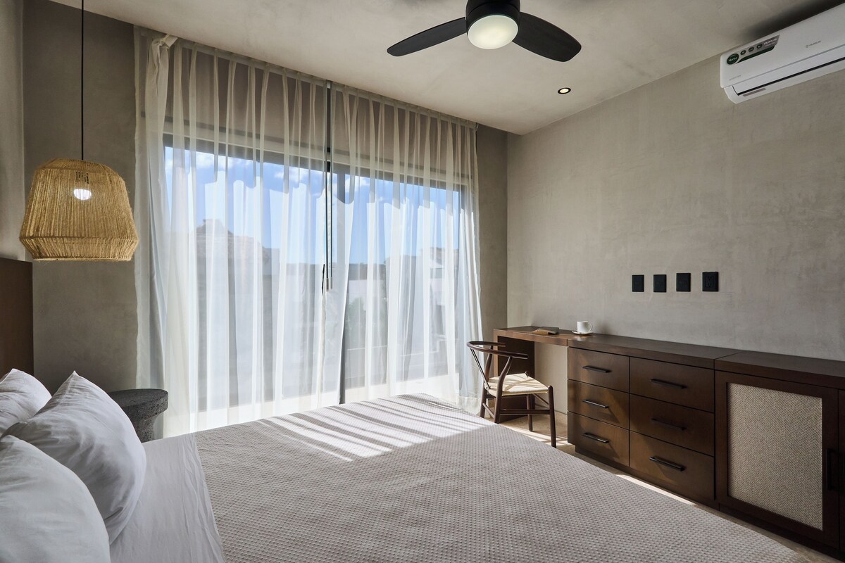 Une chambre à coucher avec un lit, un bureau et une chaise. On y trouve également un ventilateur de plafond et un appareil de climatisation.