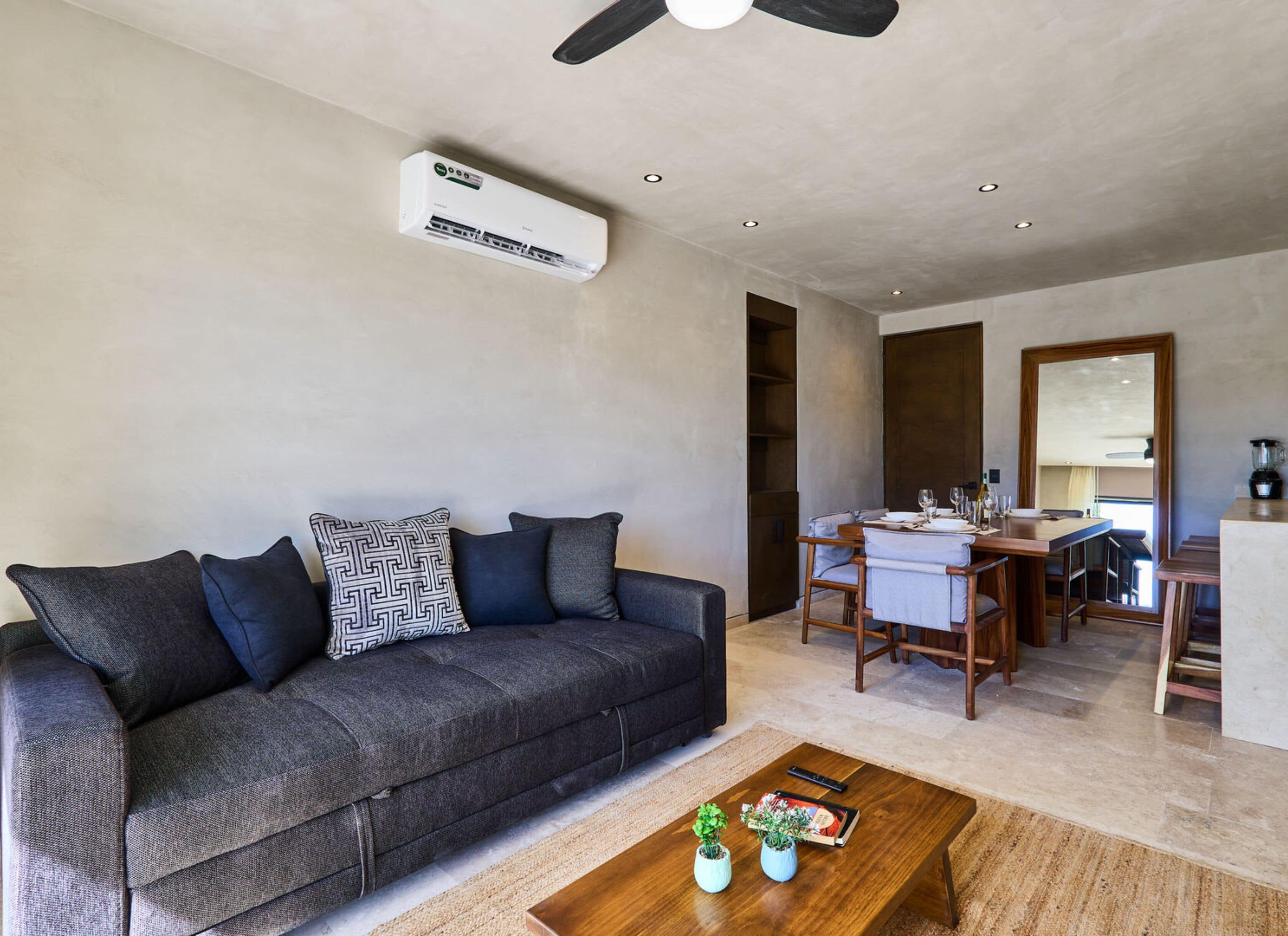 A modern living room with a sofa, coffee table, and a dining area with a table and chairs.