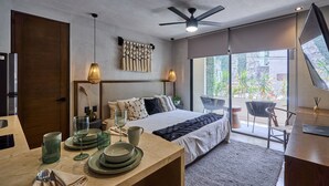 Ein modernes Schlafzimmer mit Bett, Nachttisch und Blick ins Freie durch große Fenster.