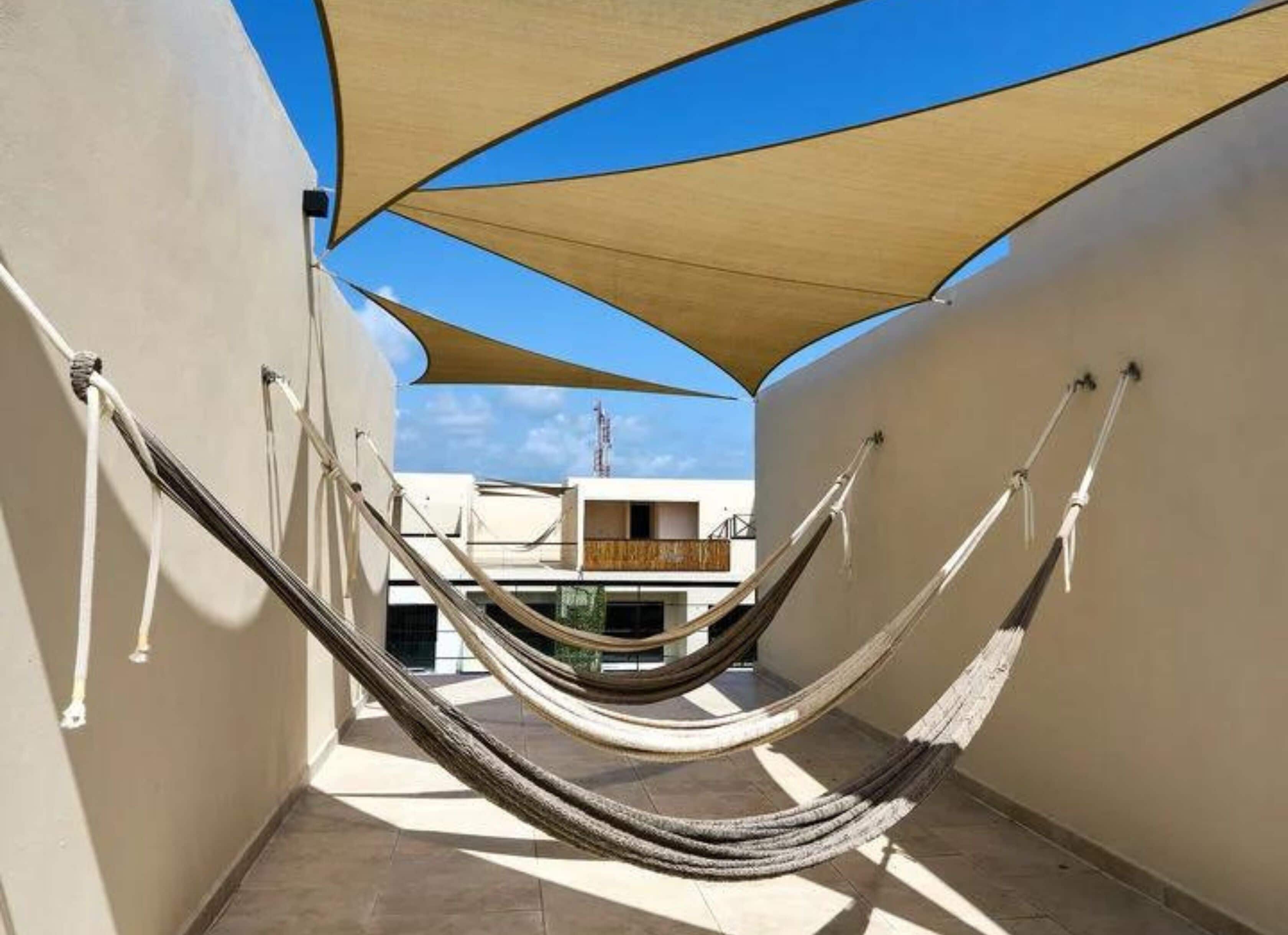 A hammock set up between two walls with a view of a building in the background.