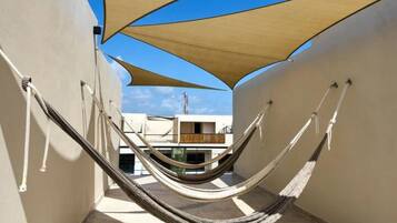 A hammock set up between two walls with a view of a building in the background.