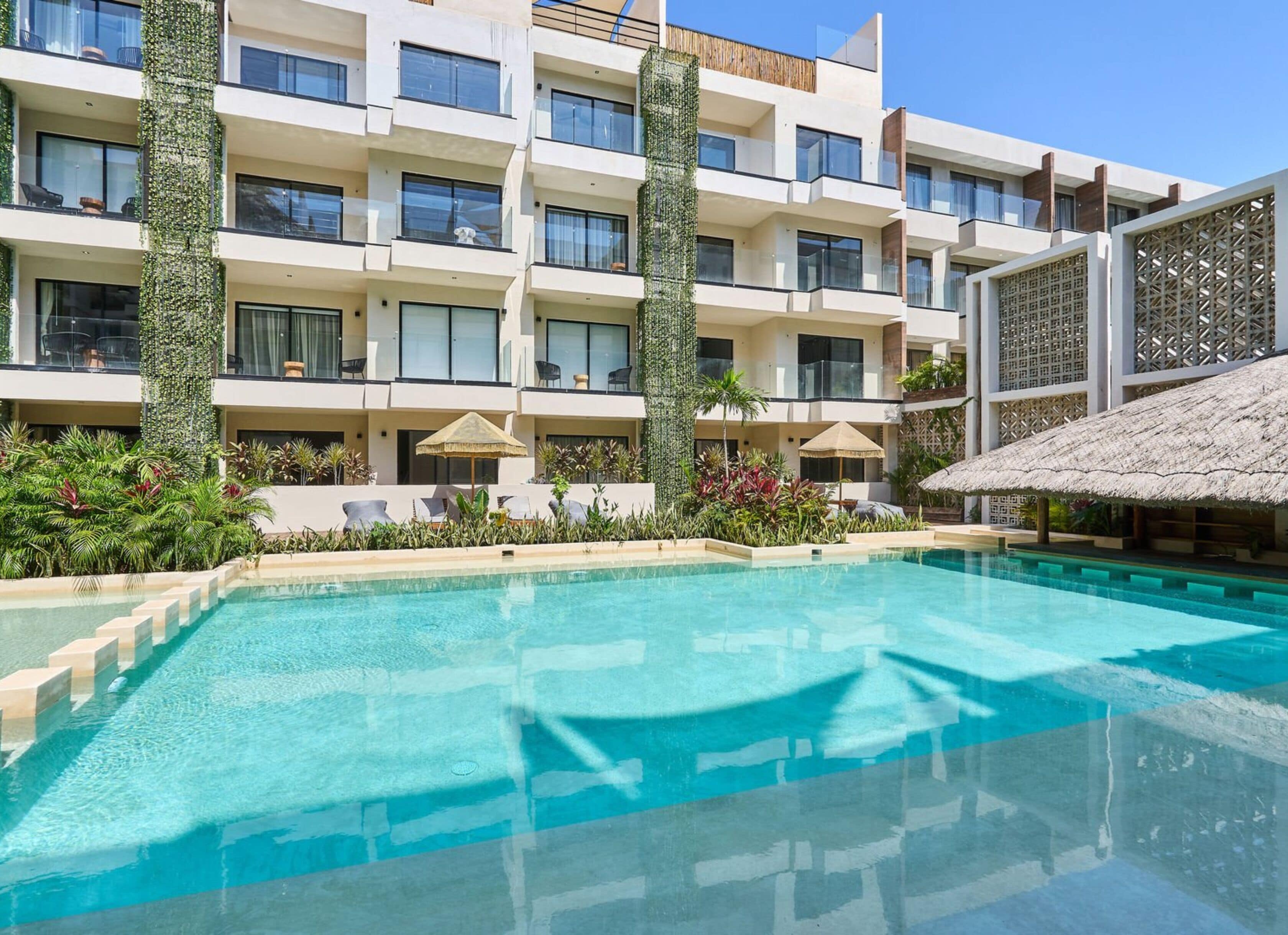 Un hôtel moderne doté d’une piscine, de nombreux balcons et d’une végétation luxuriante.