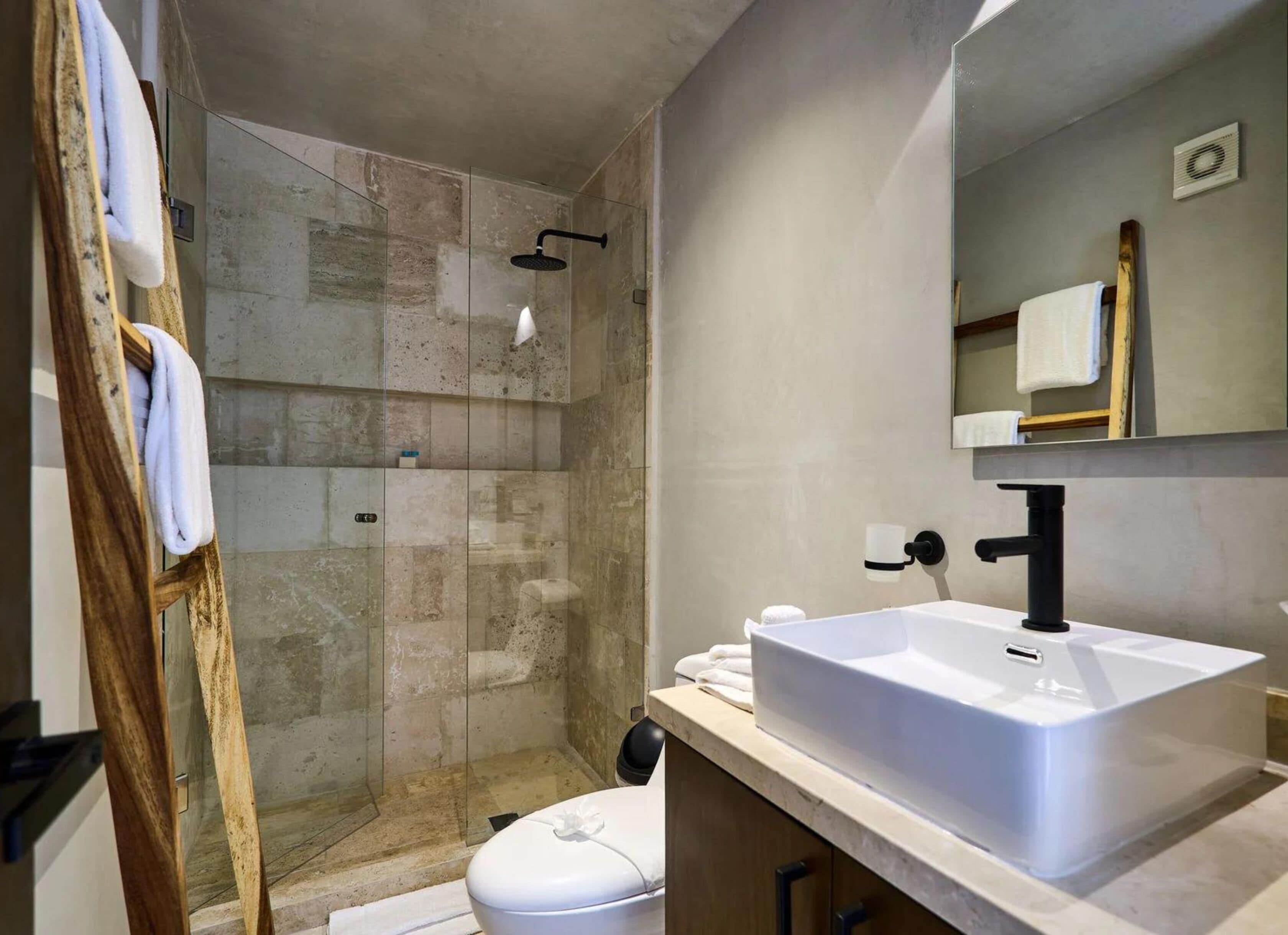 A modern bathroom with a glass-enclosed shower, a white sink, and a wooden vanity.
