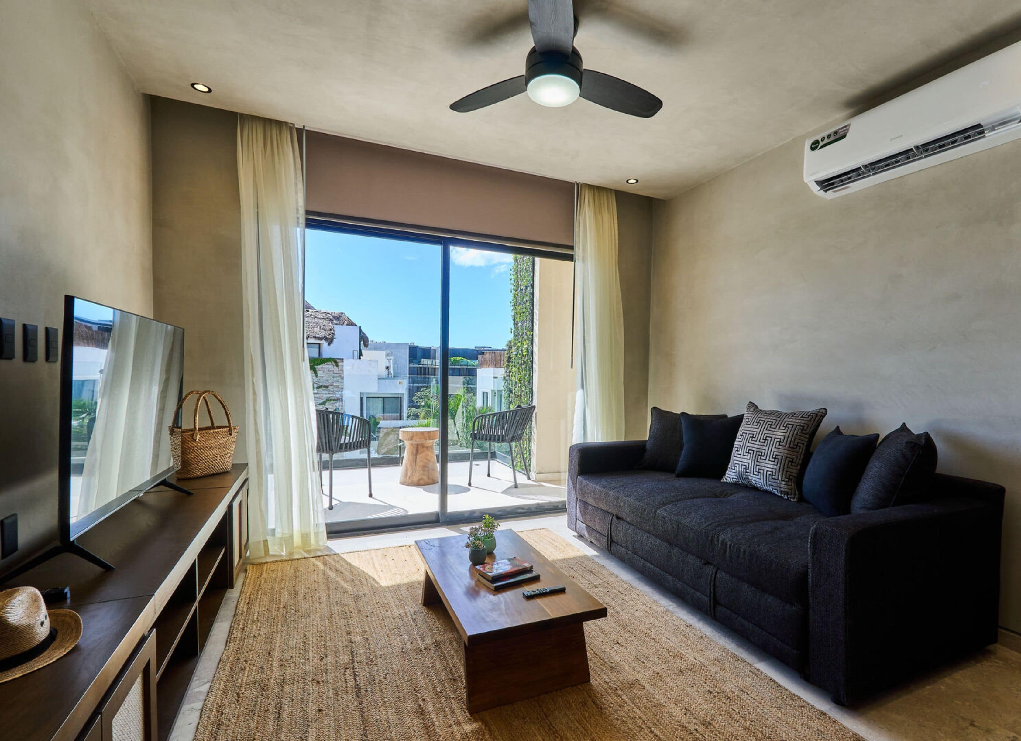 A modern living room with a dark sofa, a wooden coffee table, and a flat-screen TV.