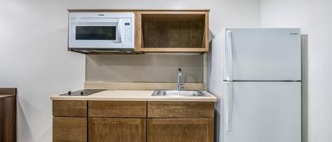 Una cocina compacta con microondas, lavamanos y refrigerador.