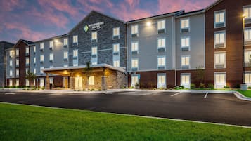 A multi-story hotel with a stone facade, a covered entrance, and a parking lot.